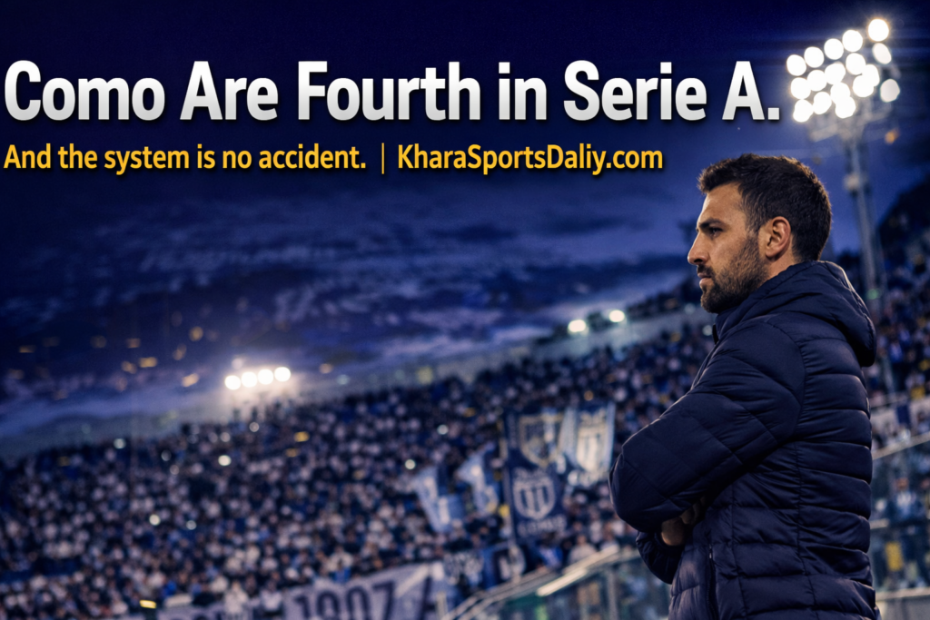 Cesc Fabregas standing at the edge of the technical area during a Como 1907 Serie A match, stadium floodlights illuminating the touchline against a deep blue twilight sky